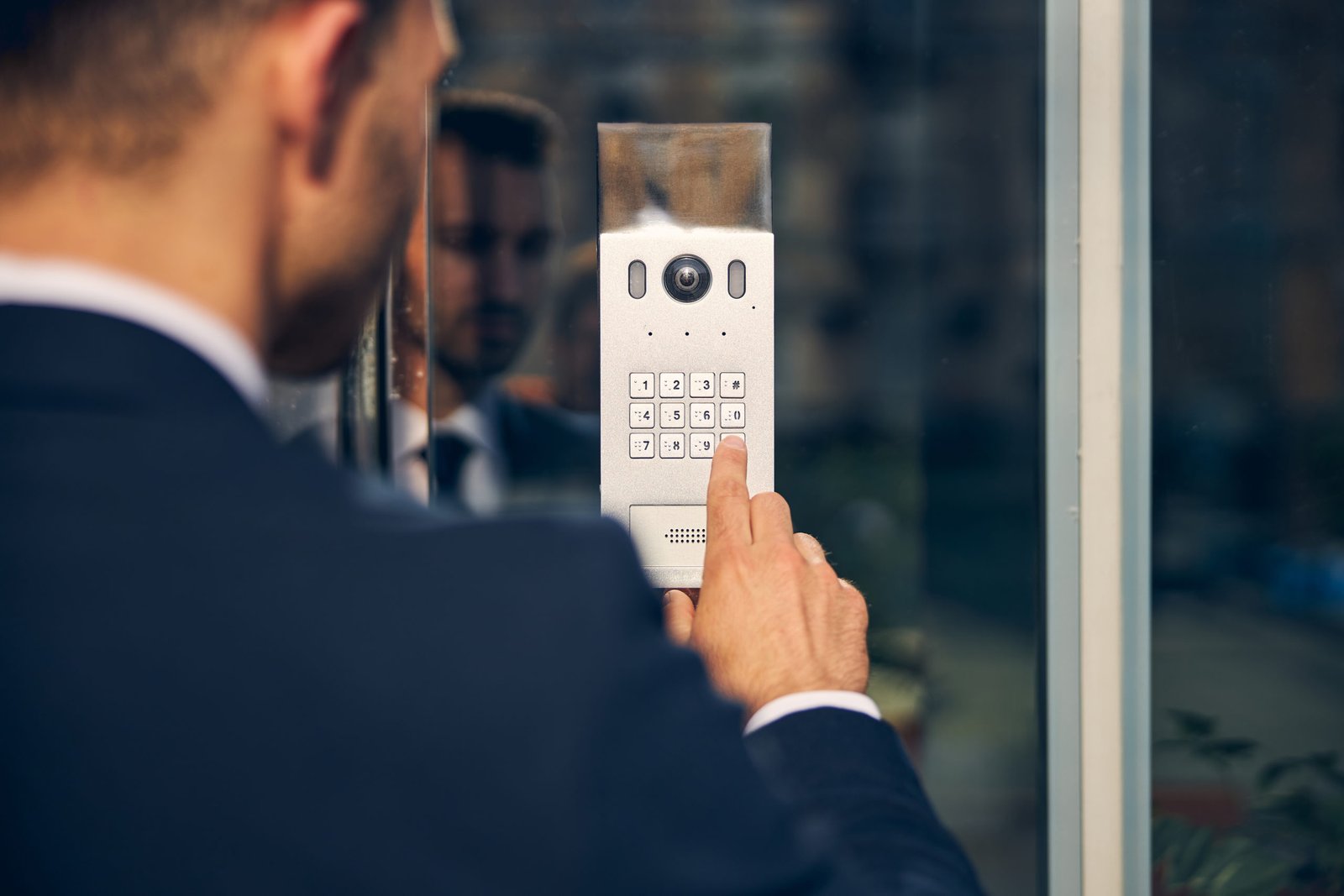 Young man trying to enter building touching buttons