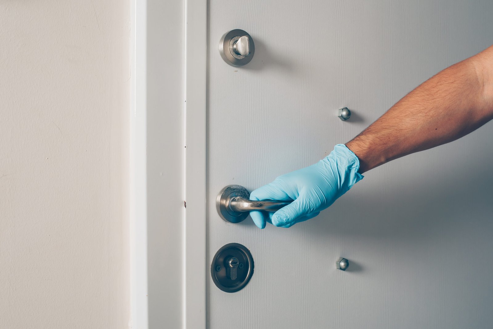 Portrait of a man at room opening the door with hands in gloves coronavirus